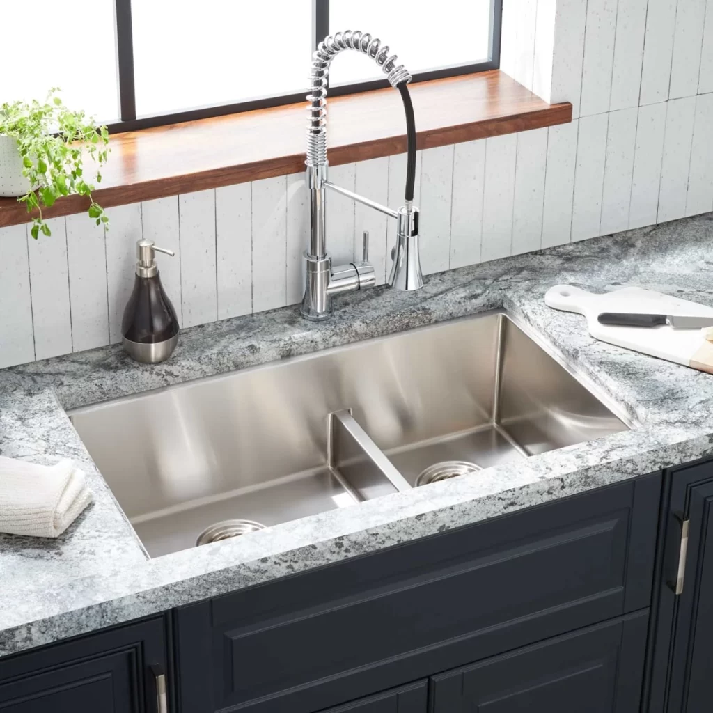 A sleek undermount stainless steel sink with a double bowl design, integrated into a granite countertop