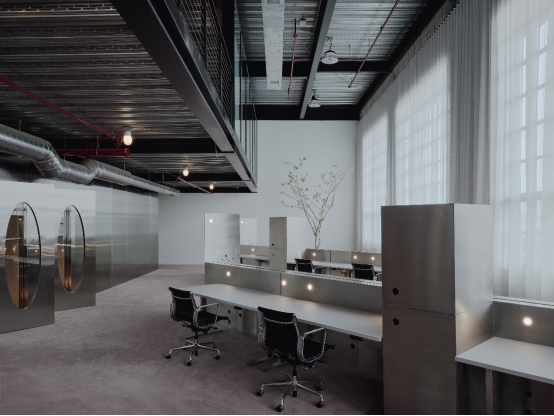 Industrial studio desks integrated with custom stainless steel fabrication for privacy dividers and metal cabinets